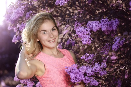 Young beautiful woman near the flowering shrubの写真素材