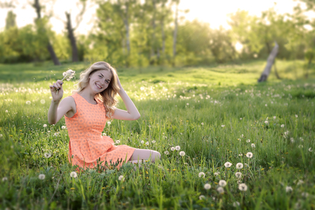 Beauty blond model girl and smelling dandelion flowers.の写真素材