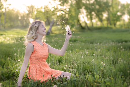 Beauty blond model girl and smelling dandelion flowers. Allergy free. Healthy Smiling Girl portraitの写真素材