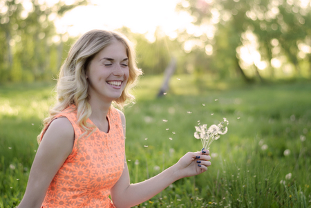 Beauty blond model girl and smelling dandelion flowers. Allergy free. Healthy Smiling Girl portraitの写真素材