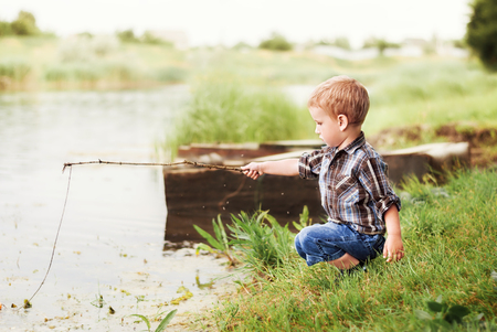 Little boy is fishing at sunset on the riverの写真素材