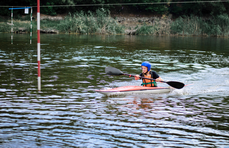 young teenager girl actively manages a sports kayak boat on a beautiful riverの写真素材