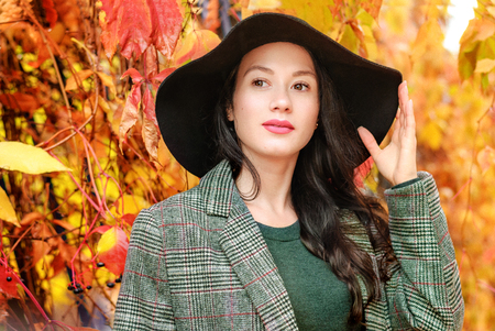 beautiful girl in a hat on a background of autumn parkの写真素材
