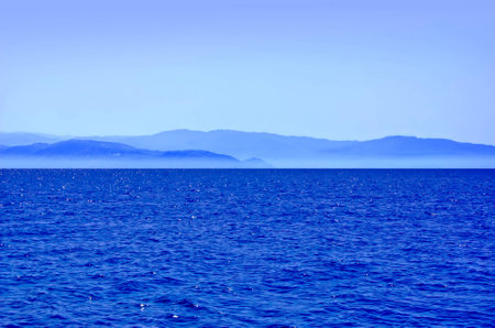 Seascape with blue ridge mountains in mist at the horizonの写真素材