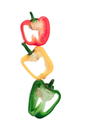 Pyramid made of slices of red, yellow and green bell peppers on isolated white backgroundの写真素材
