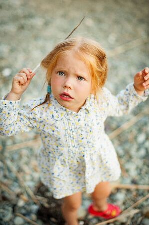 Portrait of a little girl with red hair and a feather in her hairの写真素材