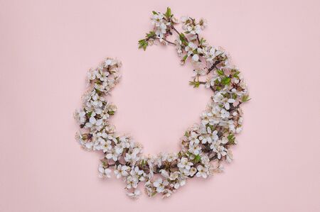 Round frame wreath made of spring flowers on pink background. Top view. Flat lay. The concept of...