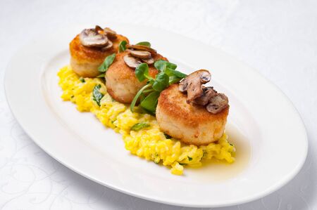 Cutlets with mushrooms on a pillow of risotto in a white plate on a white background. Isolate