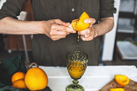 Woman making orange juice at home. Preparation of orange fresh. Healthcare concept. Soft focus