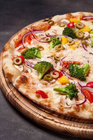 Vegetable pizza on a wooden board. Dark background. Vertical photographyの写真素材