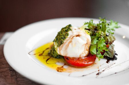 Italian burrata cheese with tomatoes, herbs, pesto and olive oil.の写真素材