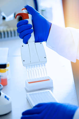 Variable volume multichannel pipette. Medical worker, scientist, laboratory assistant in rubber...