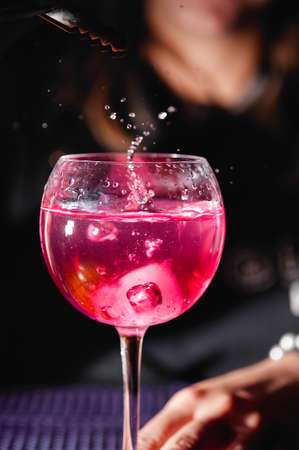 Splash of drink in a glass. Bartender preparing a cocktailの写真素材