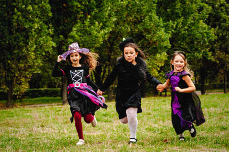 Happy kids in halloween costumes running on the lawnの写真素材