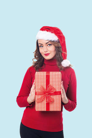 Vertical portrait of a woman in red clothes and santa hat with a gift in her hands