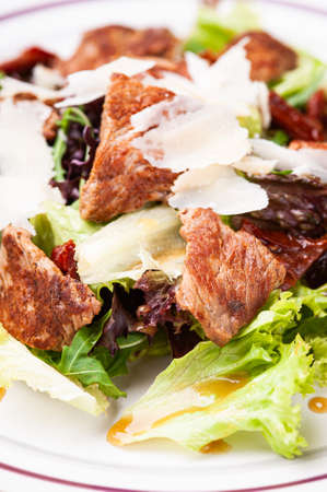 Closeup fresh salad with meat, lettuce, parmesan and sauce.の写真素材