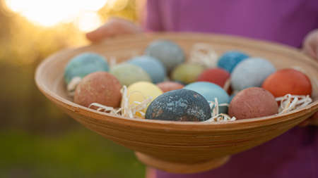 Girl holding a wooden plate with easter eggsの写真素材
