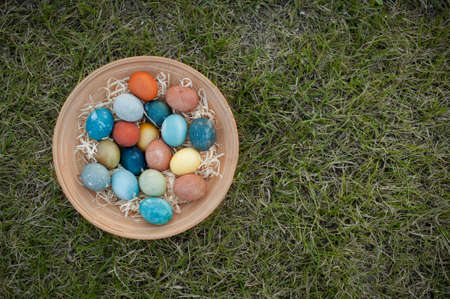 Easter eggs in a wooden plate on a background of green grass Copy Spaceの写真素材