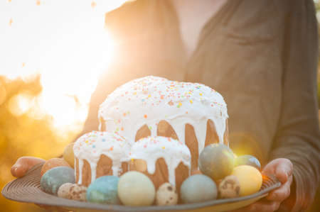Girl holding a wooden plate with easter cake and eggs