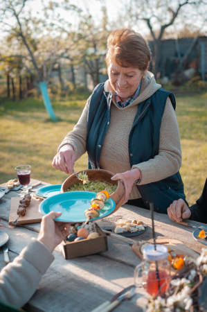 The family gathered at a festive table in the garden to celebrate Easterの写真素材
