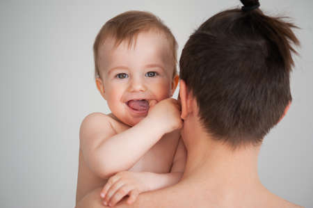 father holding a cute little smiling baby in his arms on a white backgroundの写真素材