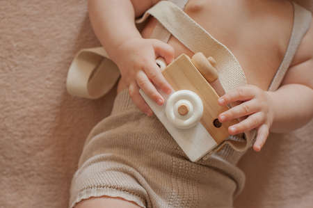 Wooden toy-camera in the hands of a babyの写真素材