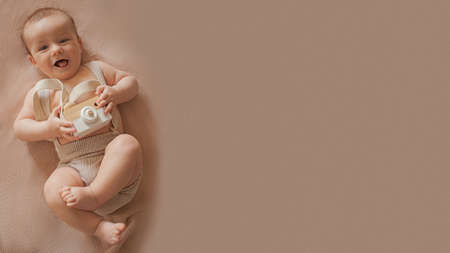 Kid with a wooden camera lies on a beige backgroundの写真素材