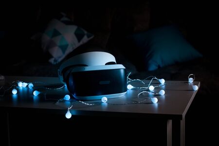 The helmet of virtual reality. New experience gained in the game. Amazing emotions, cool rest, reboot. Virtual reality glasses lie on the table in neon lights. The concept of visual reality.の写真素材