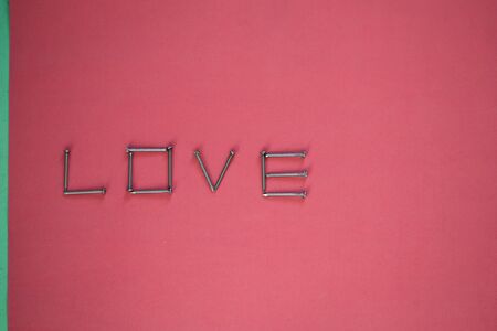 The inscription LOVE made of nails. Metallic inscription for the bottom of Valentine's Day. Concept of love. Space for text.の写真素材