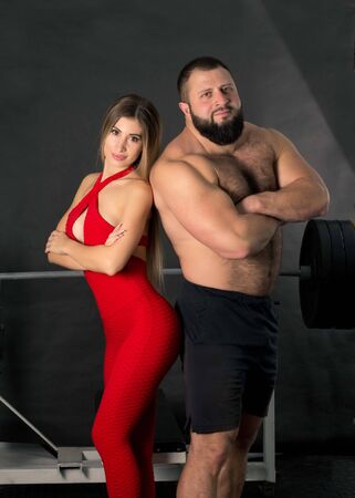 A couple of sporty people, a strong man and a fragile girl in getting ready for training in the gym. Beautiful, sporty, trained body, powerlifter and fitness girl. Beautiful couple man and woman.の写真素材