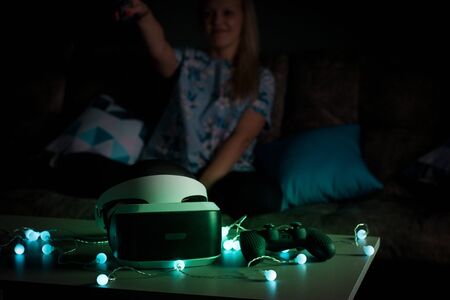 Helmet of virtual reality. Girl wants to get experience using glasses of a VR headset. Amazing emotions, cool rest, reboot. Virtual reality glasses lie in neon lights. Concept of visual reality.の写真素材