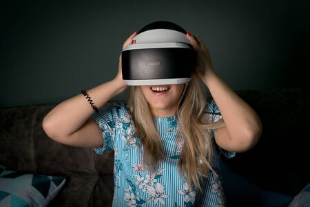 Helmet of virtual reality. Girl wants to get experience using glasses of a VR headset. Amazing emotions, cool rest, reboot. Virtual reality glasses lie in neon lights. Concept of visual reality.の写真素材
