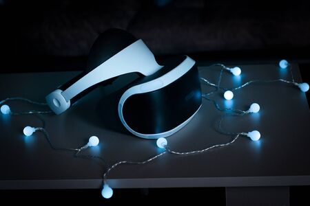 The helmet of virtual reality. New experience gained in the game. Amazing emotions, cool rest, reboot. Virtual reality glasses lie on the table in neon lights. The concept of visual reality.の写真素材