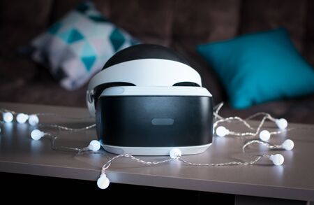 The helmet of virtual reality. New experience gained in the game. Amazing emotions, cool rest, reboot. Virtual reality glasses lie on the table in neon lights.の写真素材