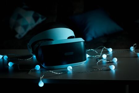 The helmet of virtual reality. New experience gained in the game. Amazing emotions, cool rest, reboot. Virtual reality glasses lie on the table in neon lights.の写真素材