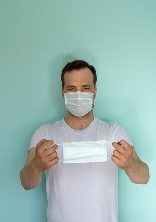 Portrait of attractive man in a medical mask and a glove on a blue background. Pandemic Protection Concept. No to coronovirus. Covid-19.の写真素材