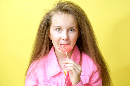 Cool girl with a fashionable hairstyle in a pink jacket with a pink lollipopの写真素材