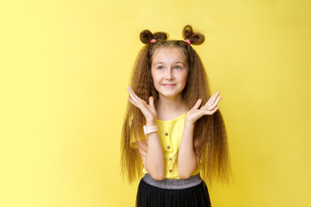 Cool cute girl with a trendy hairstyle in a yellow top on a yellow background with bright emotionsの写真素材