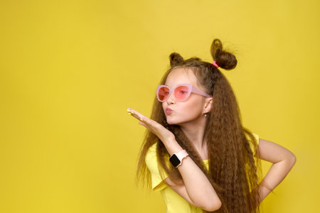 Cool cute girl with a trendy hairstyle and pink sunglasses with bright emotionson a yellow backgroundの写真素材