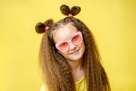 Cool cute girl with a trendy hairstyle and pink sunglasses dreams on a yellow backgroundの写真素材