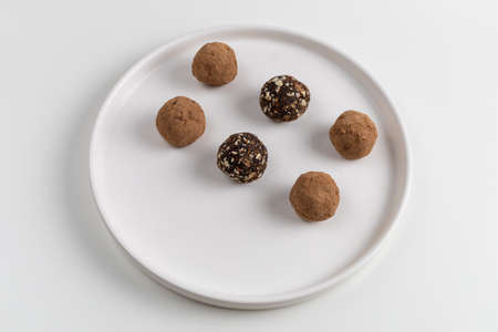 Homemade chocolate balls with dates and nuts on a white plate. Healthy dessert without sugar.