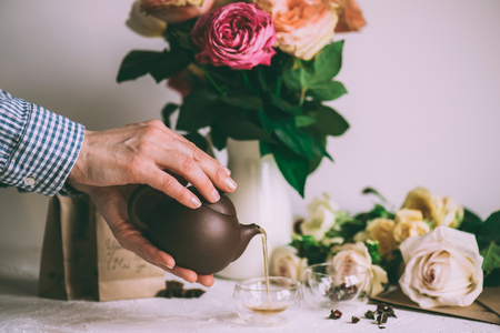 Human hands pouring Fresh herbal tea fron teapot to glassの写真素材