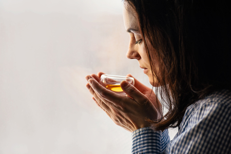 Yound dark haired woman holding glass of Fresh herbal teaの写真素材