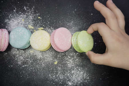 Colorful macaroni cookies, childrens pen takes a cookie, top view