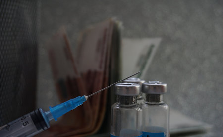 medical ampoules and syringe and money on grey background