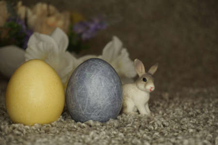 bunny figurine on Easter eggs in trendy colors - yellow and gray