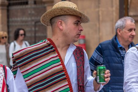 A man in traditional holiday clothes, in a hat and with a beer in his hand at the spring festival of Bando de la Huerta in Murcia, Spain, on April 23, 2019のeditorial素材