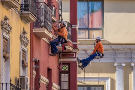 Seville, Spain, May 2, 2017. Industrial climbers are painting the facade of the house in orange.