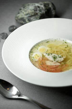 Soup with noodles surrounded by stones on a gray backgroundのeditorial素材