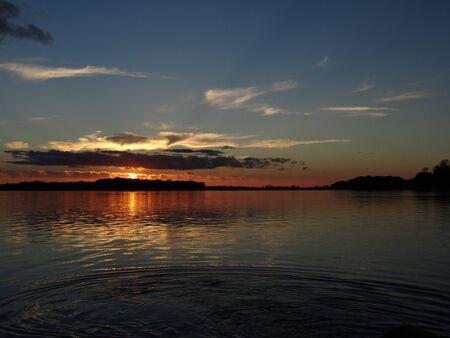 beautiful bright blue orange sunset sky and sunlit clouds over the riverの写真素材
